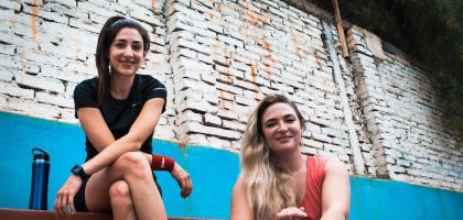 two women sitting on a wall with a brick wall behind them