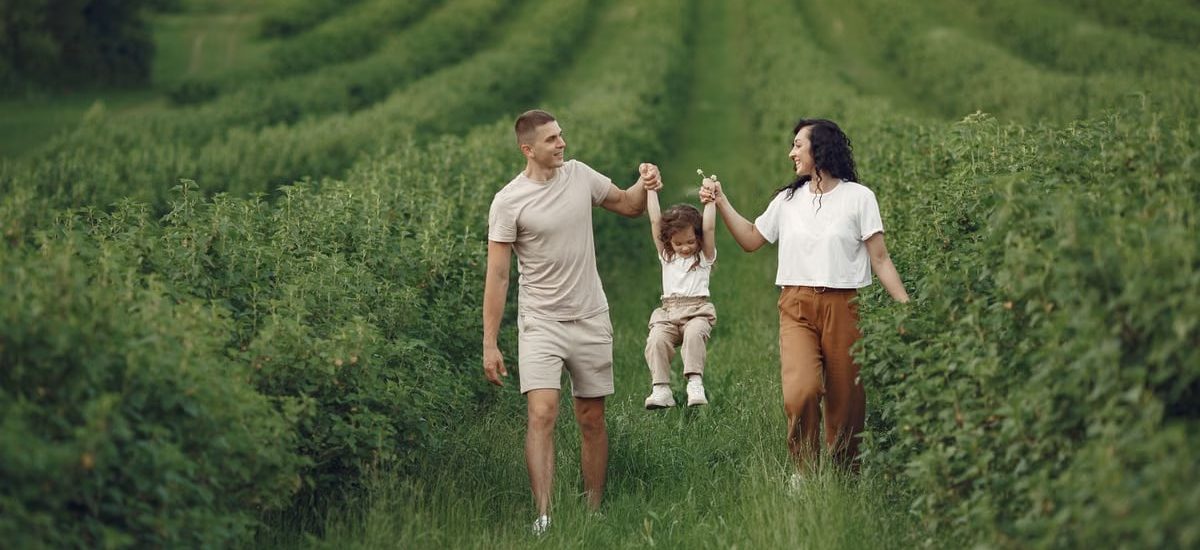 A happy family walking in a lush, green rural field together.