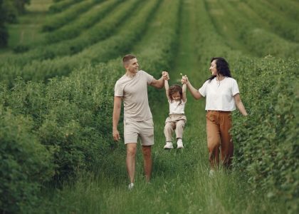 A happy family walking in a lush, green rural field together.